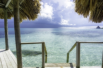 Overwater palapa with crystal clear water at Thatch Caye Resort _ Belize Retreats